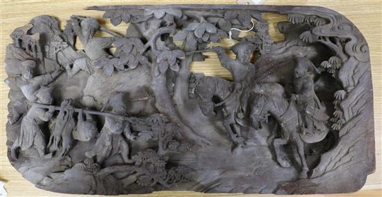 A Chinese wooden panel carved in high relief with a hunting party in a landscape, 29 x 58cm